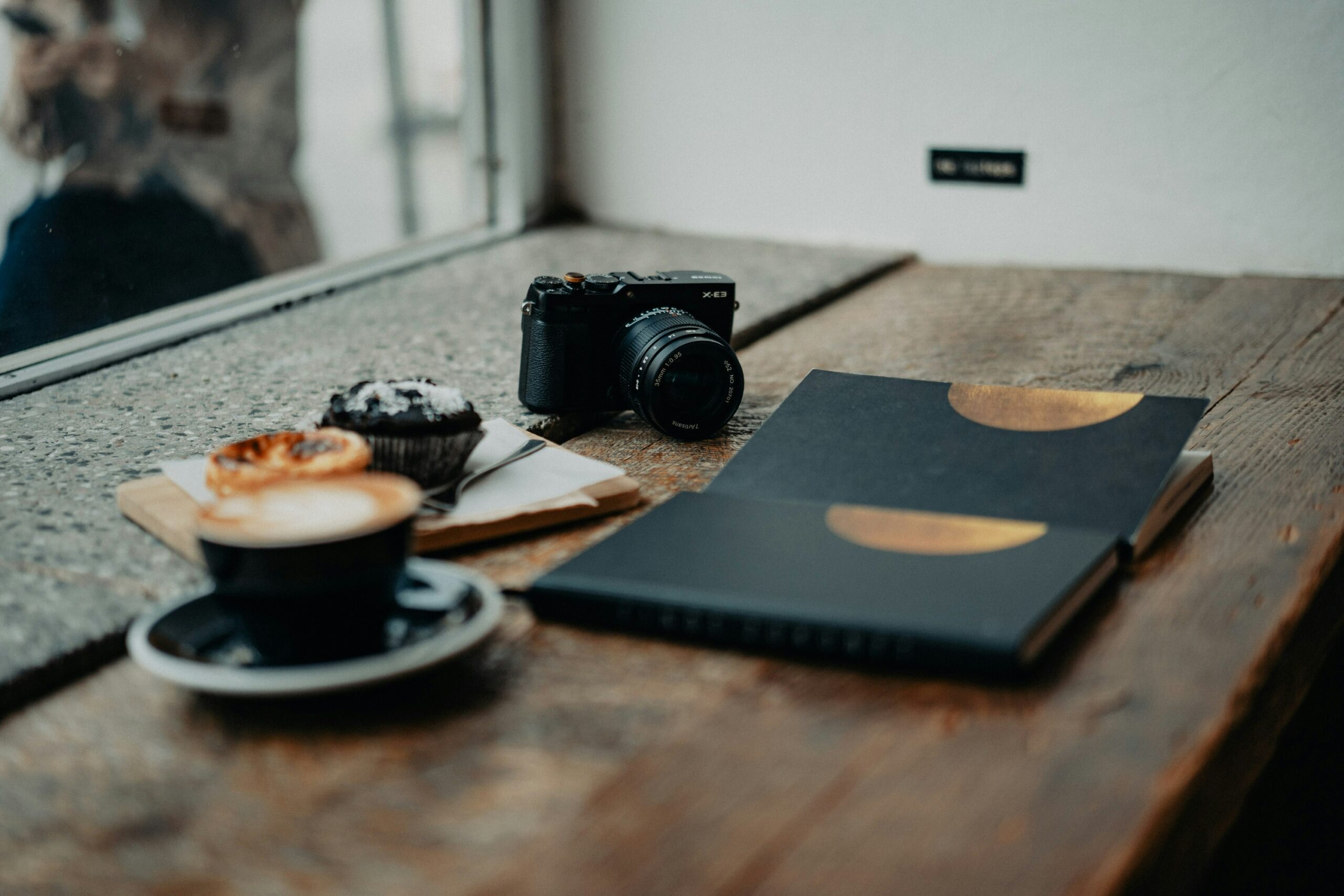 Camera, coffee and pastries on a wooden table.
